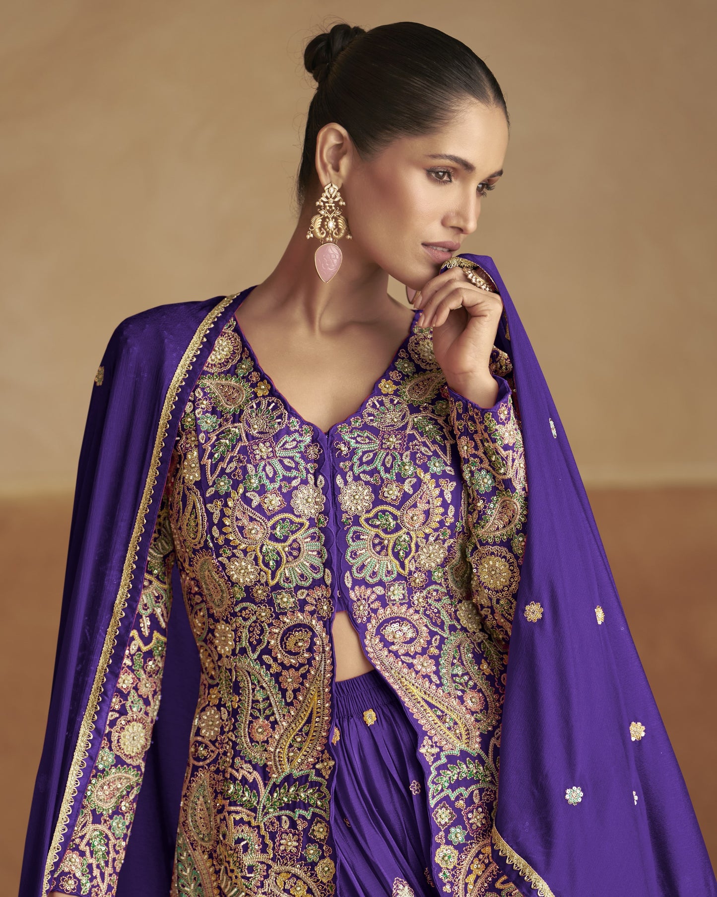 Woman wearing a traditional outfit with purple and gold patterns against a beige background