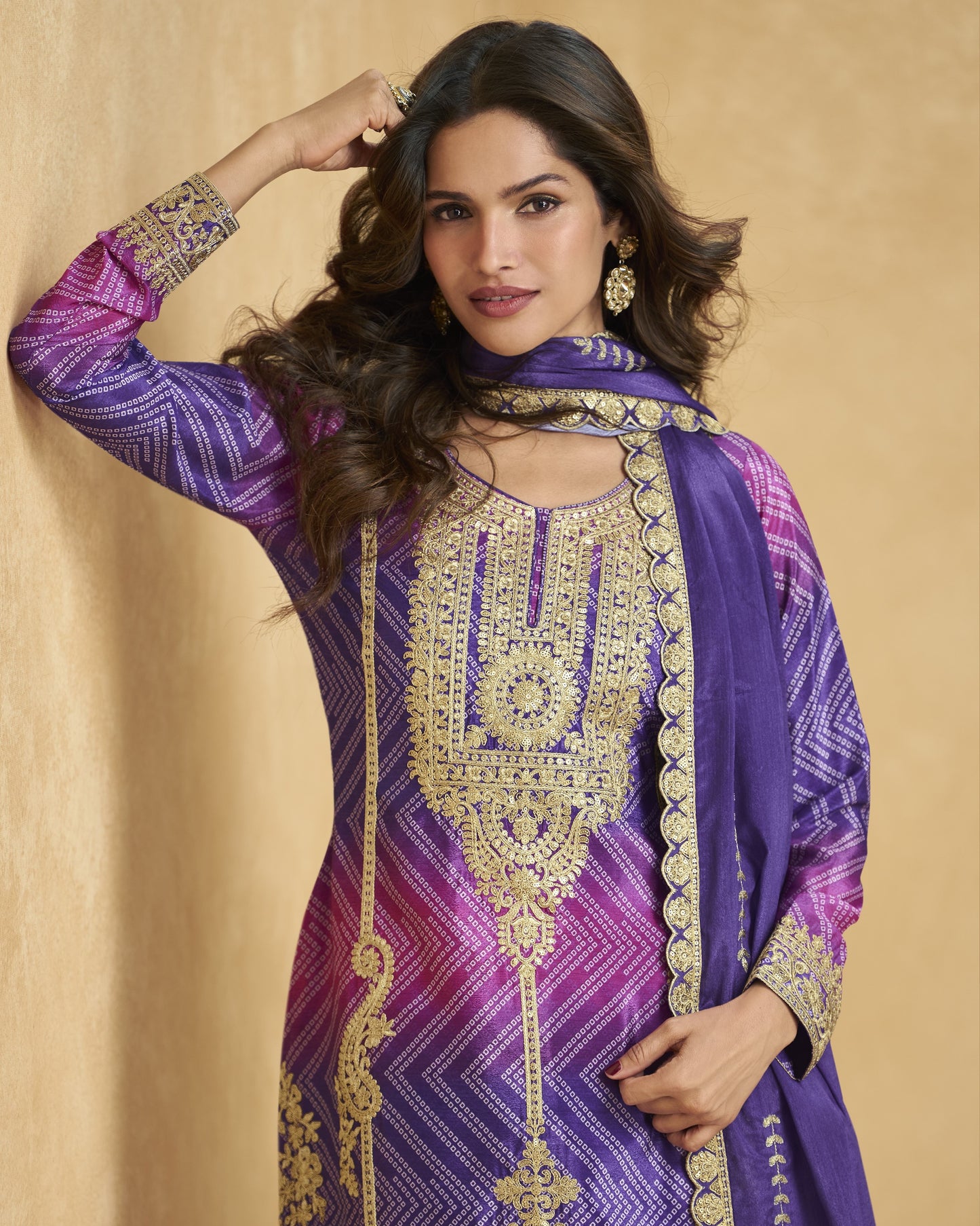 Woman wearing a purple and gold embroidered traditional outfit on a beige background