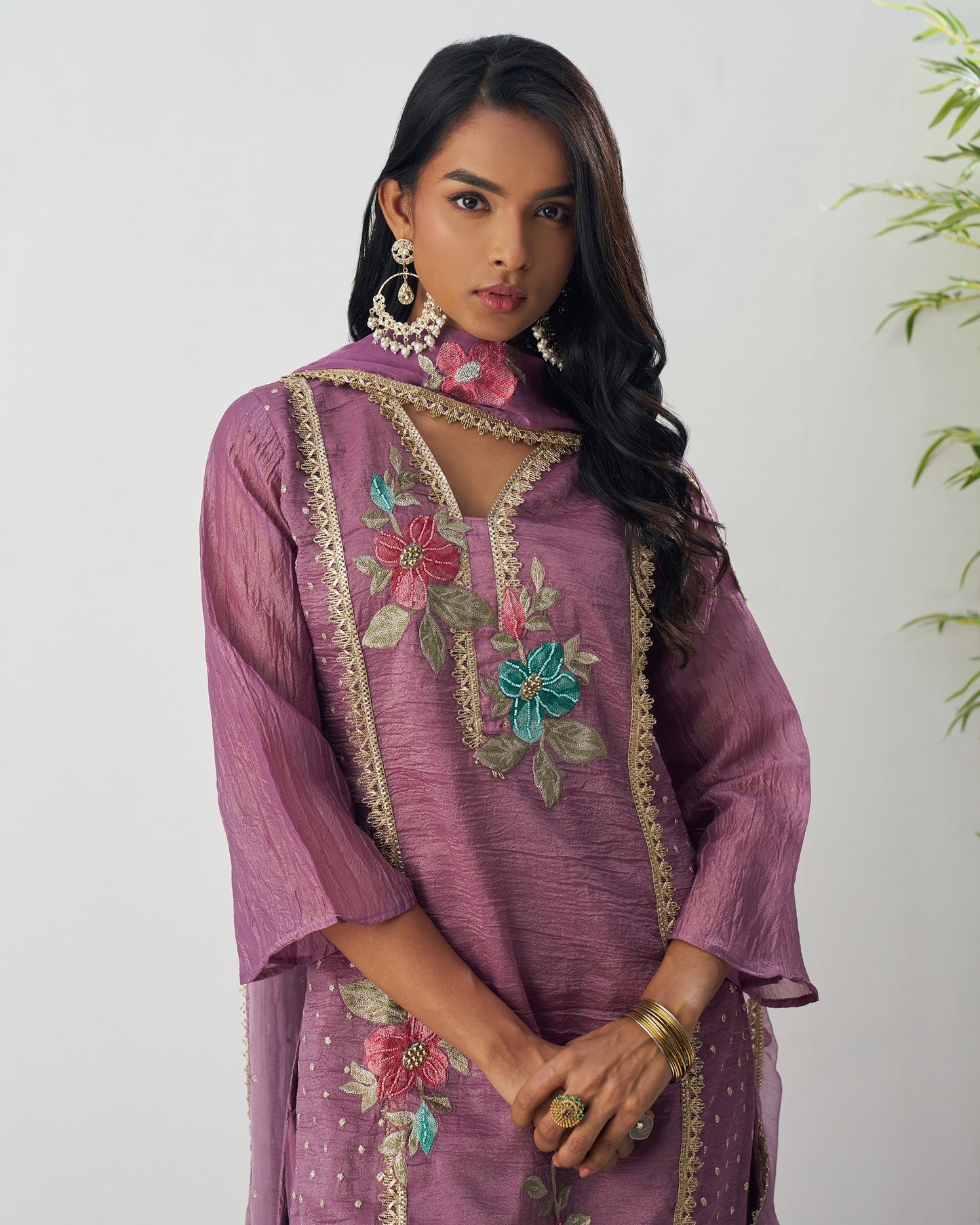 Woman wearing a purple embroidered dress with floral patterns on a white background