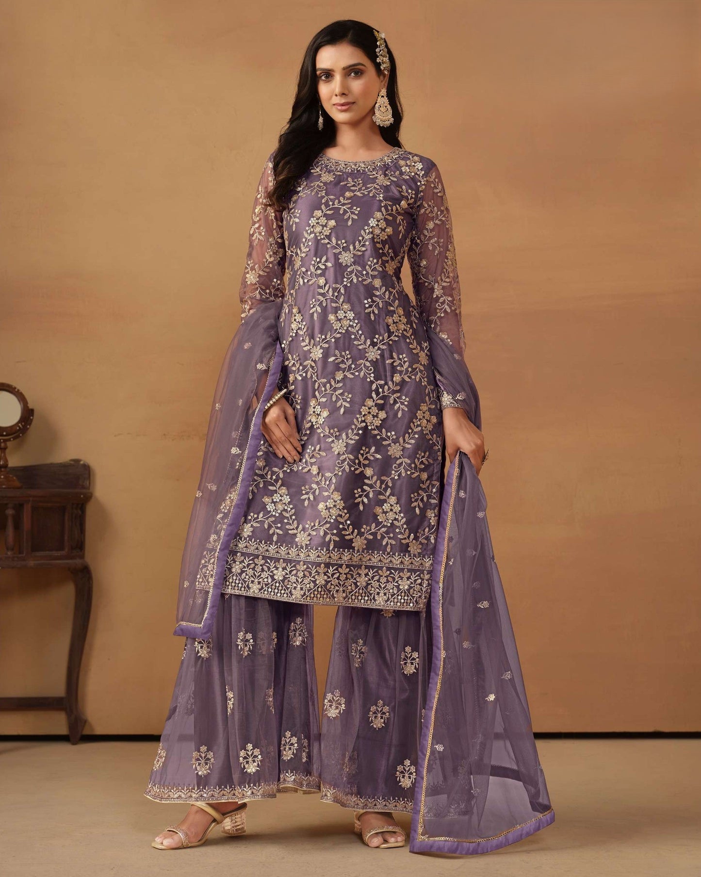 Woman wearing a purple embroidered traditional outfit on a beige background