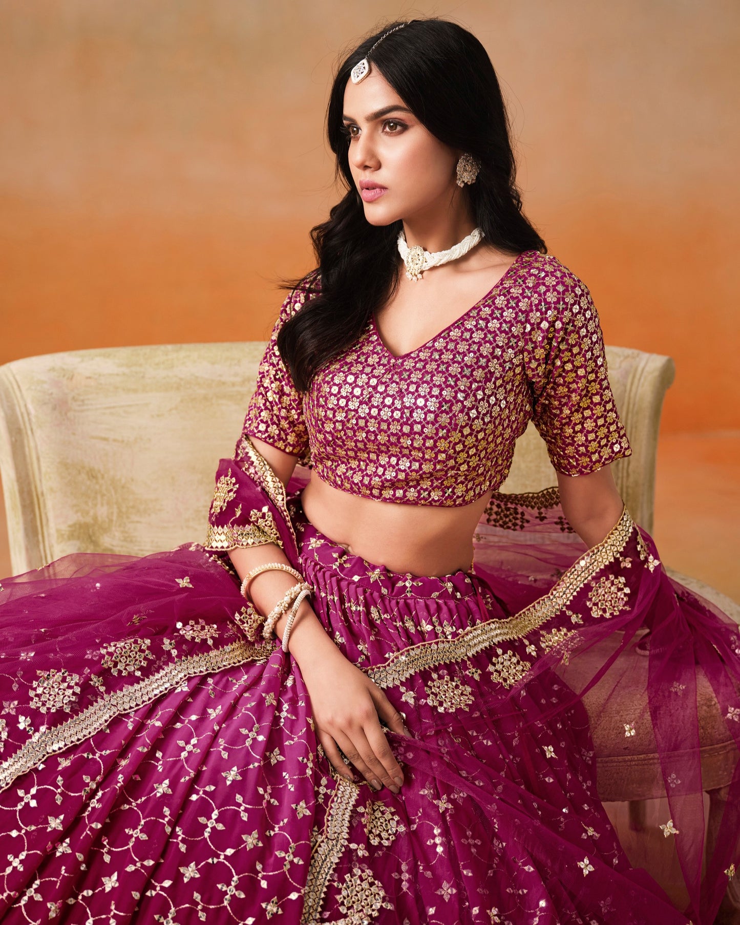 Woman in a traditional pink and gold outfit with a blurred background