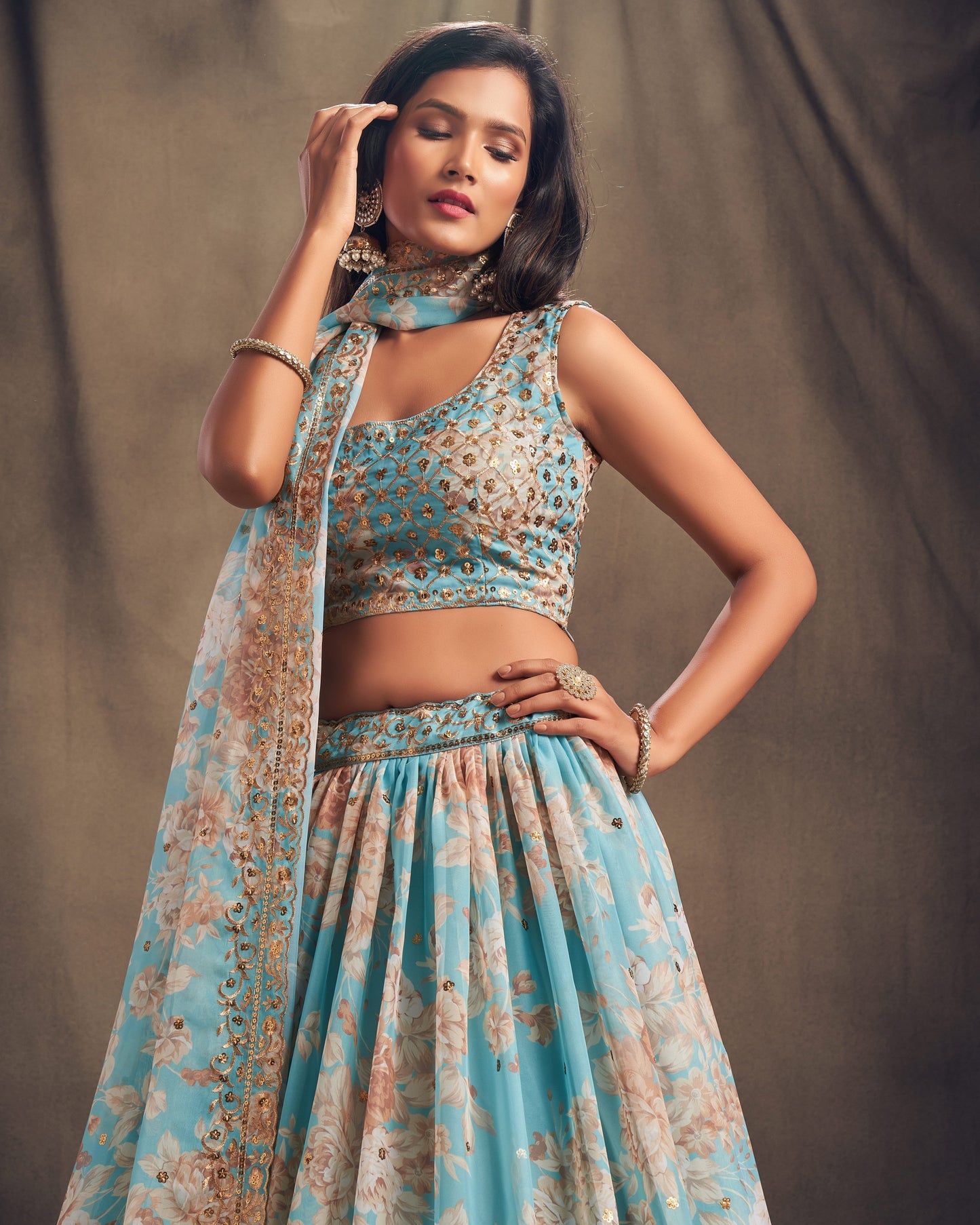 Woman wearing a floral blue and beige traditional outfit against a plain background