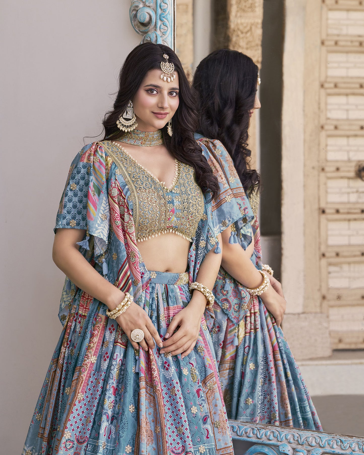 Woman in a traditional outfit with intricate patterns and jewelry, standing indoors.