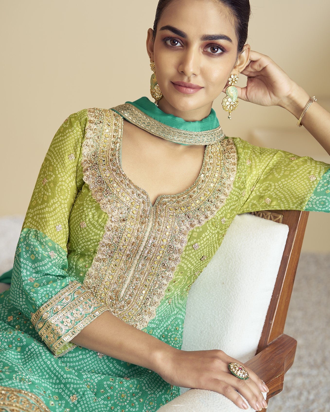 Woman wearing a green and gold traditional outfit with intricate patterns.