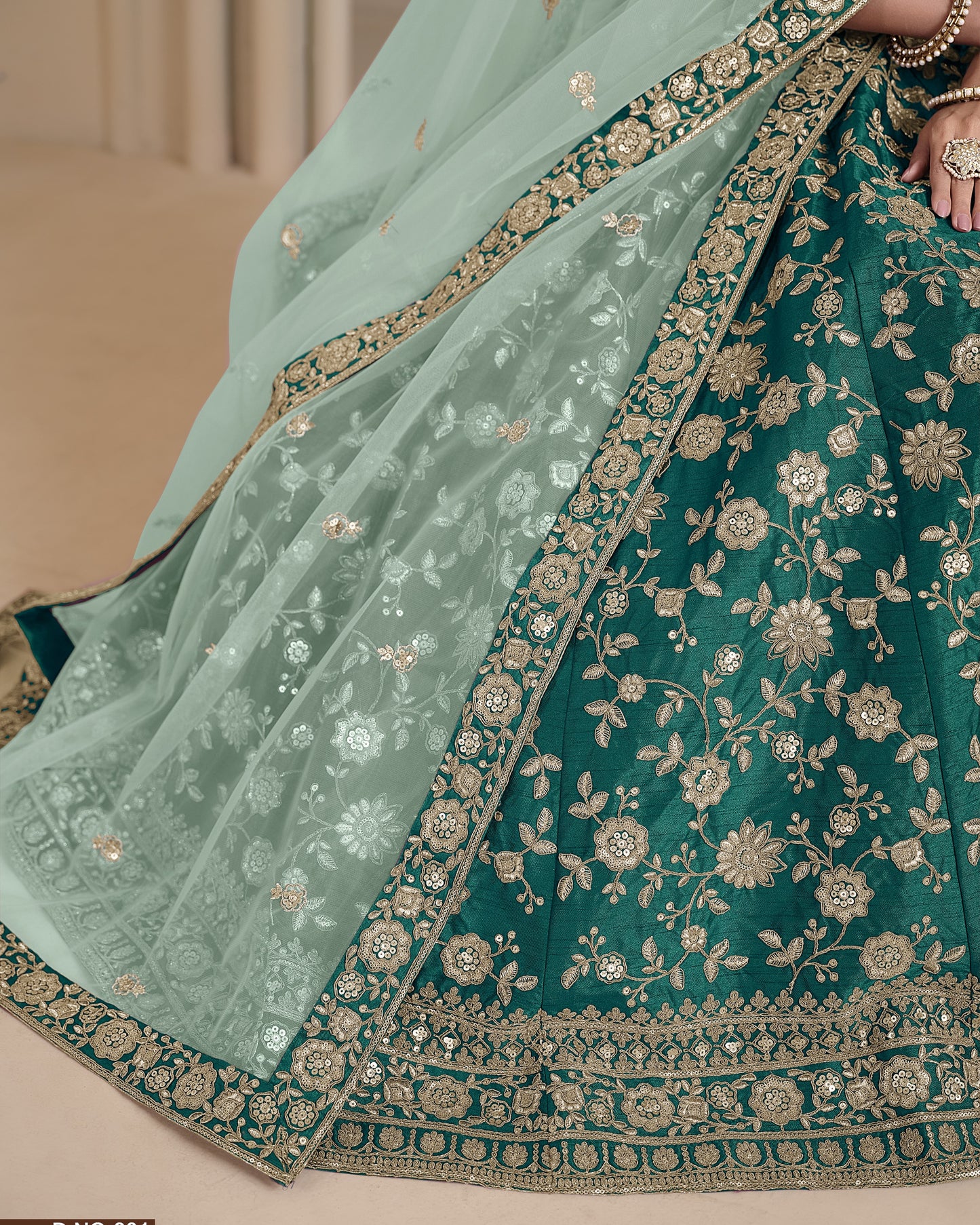 Teal and light blue embroidered saree with gold detailing on a neutral background