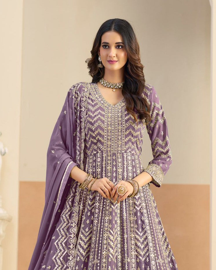 Woman wearing a purple and white embroidered traditional outfit with a matching dupatta.
