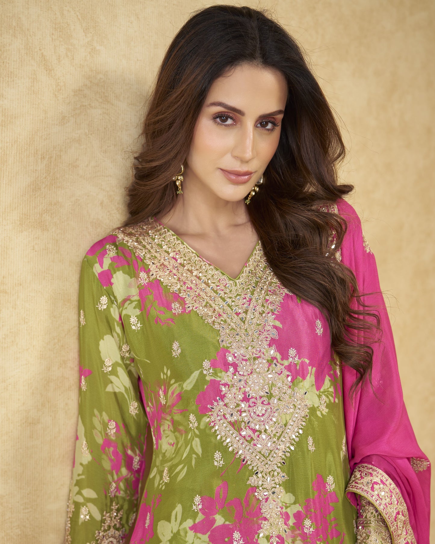 Woman wearing a green and pink traditional outfit with floral patterns on a beige background