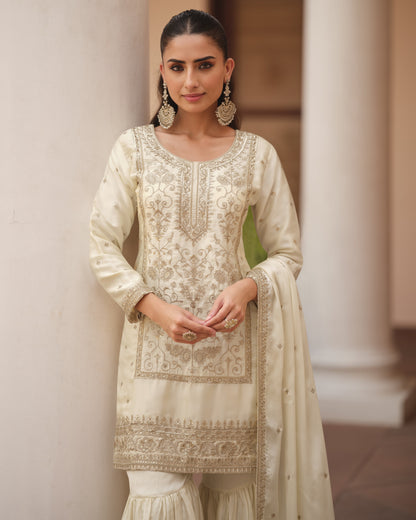 Woman wearing a cream-colored embroidered traditional outfit with a white background