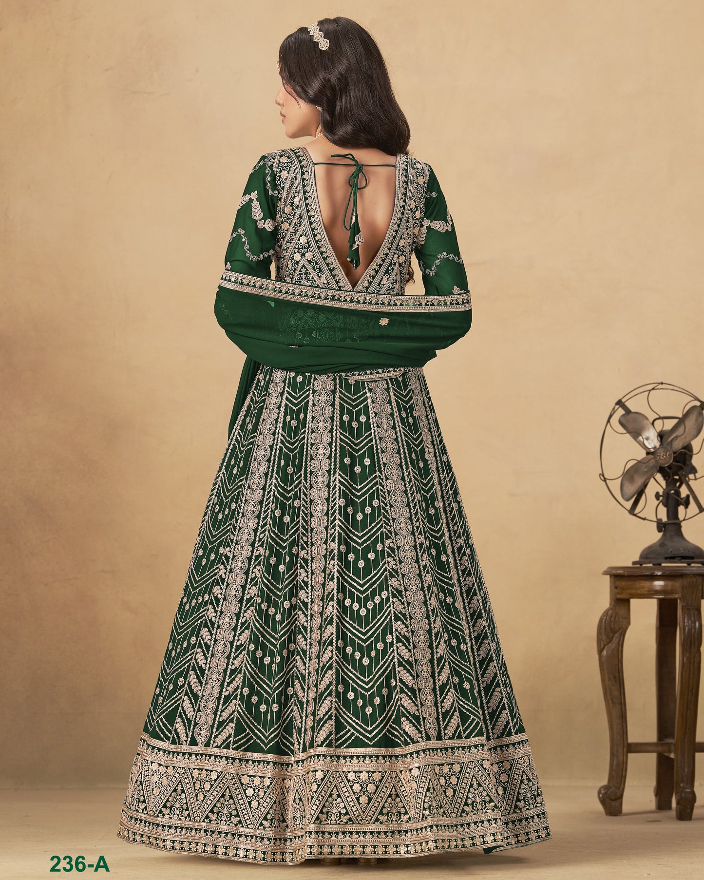 Woman wearing a green and white patterned dress with a vintage fan in the background