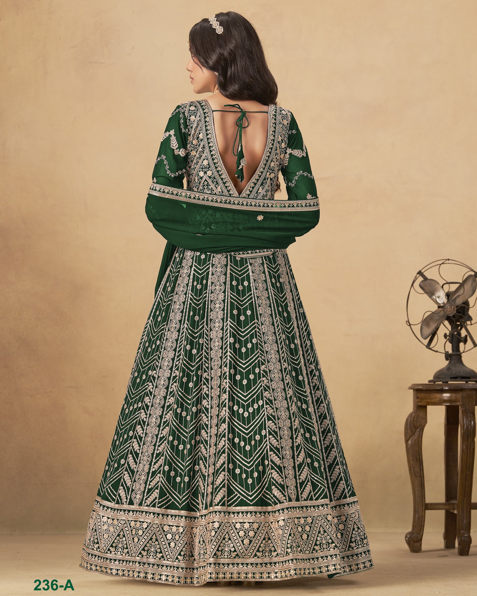 Woman wearing a green and white patterned dress with a vintage fan in the background