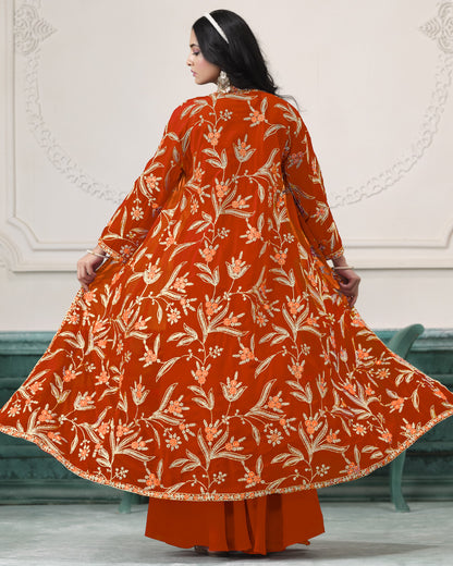 Woman wearing a rust-colored floral patterned outfit against a white wall.
