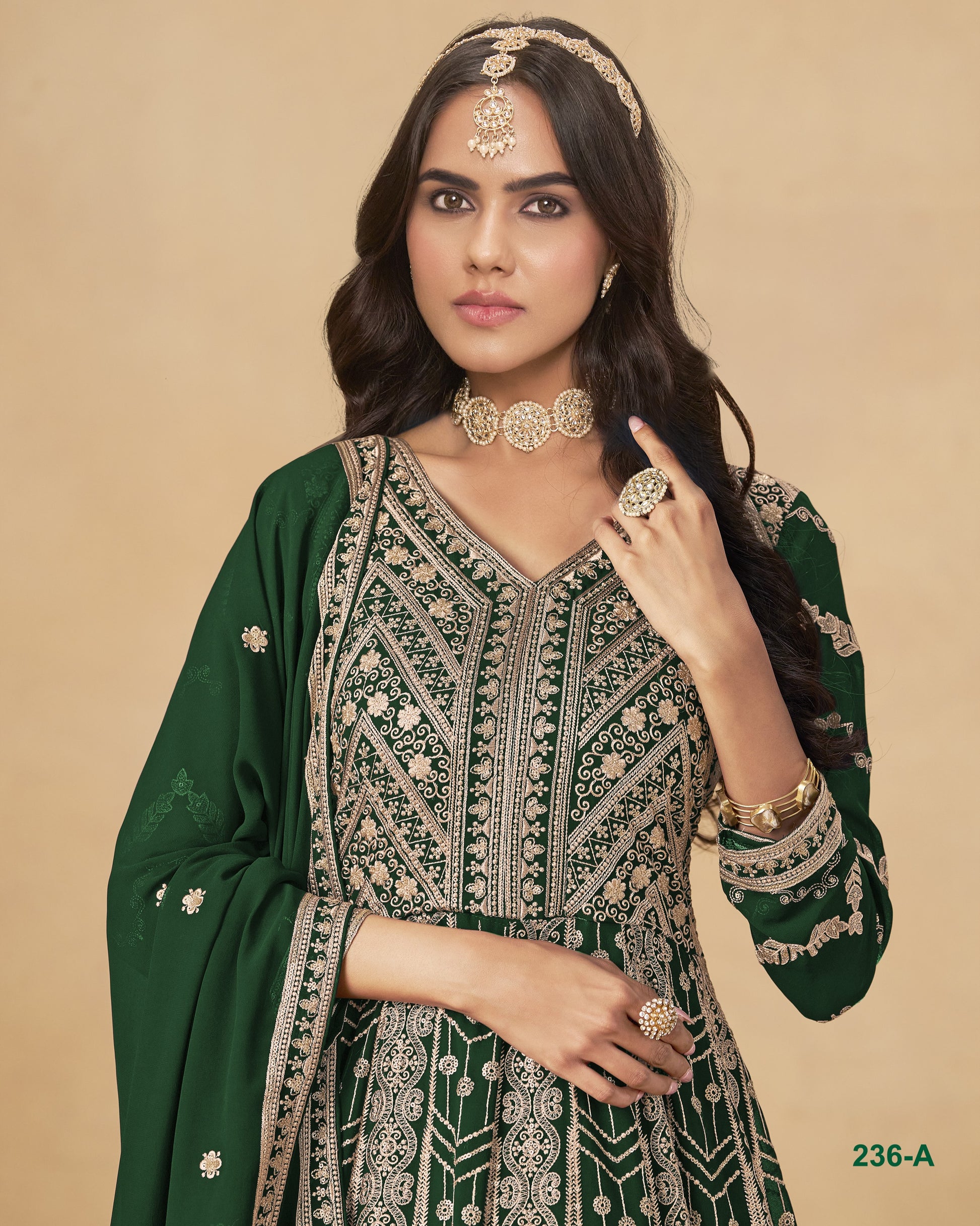 Woman wearing a green and gold traditional outfit with jewelry on a beige background
