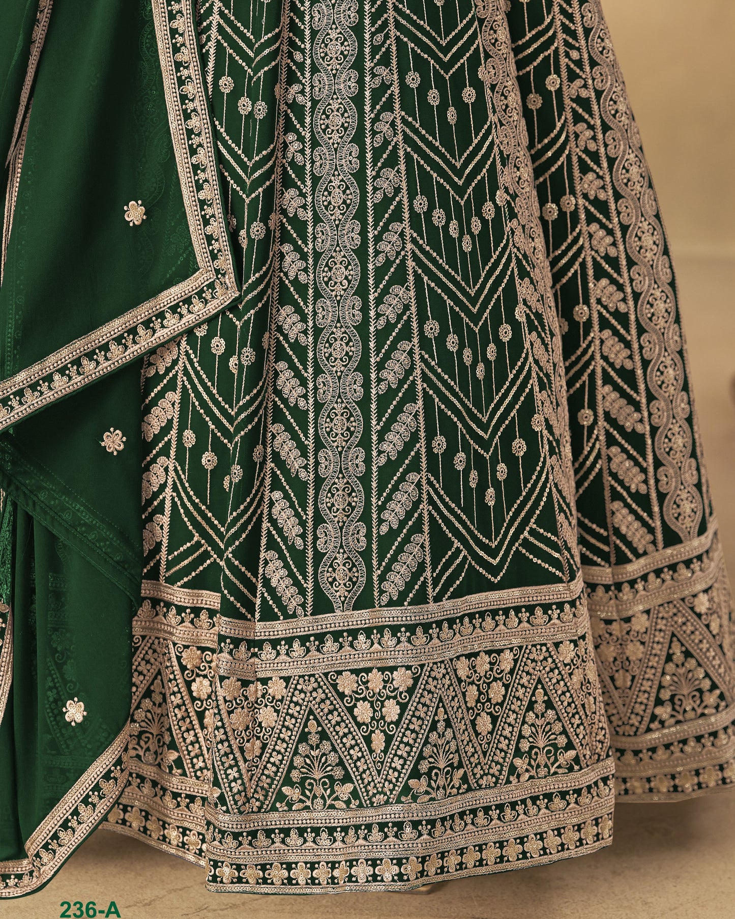 Green embroidered fabric with intricate white patterns on a beige background