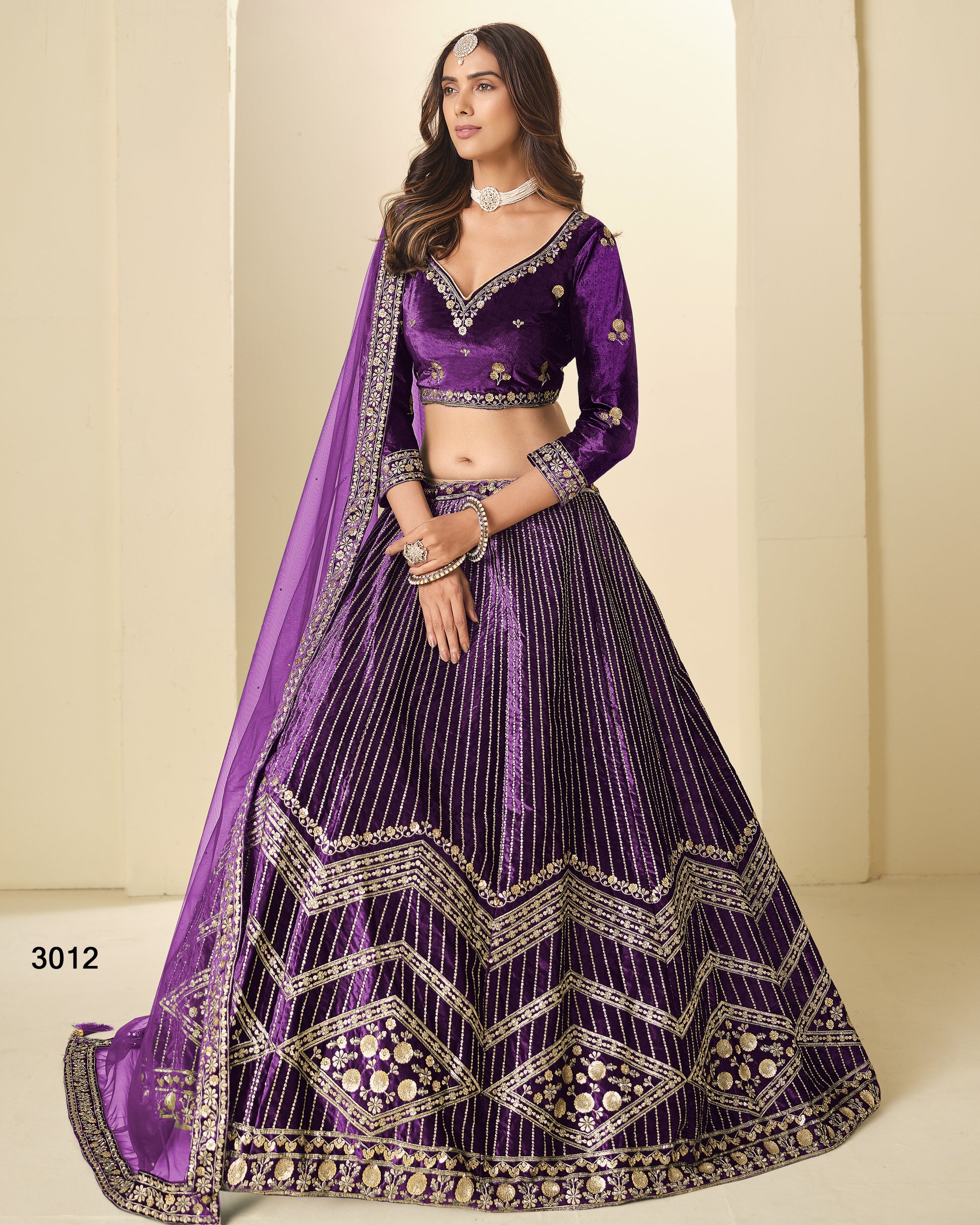 Woman wearing a purple embroidered lehenga with a plain background