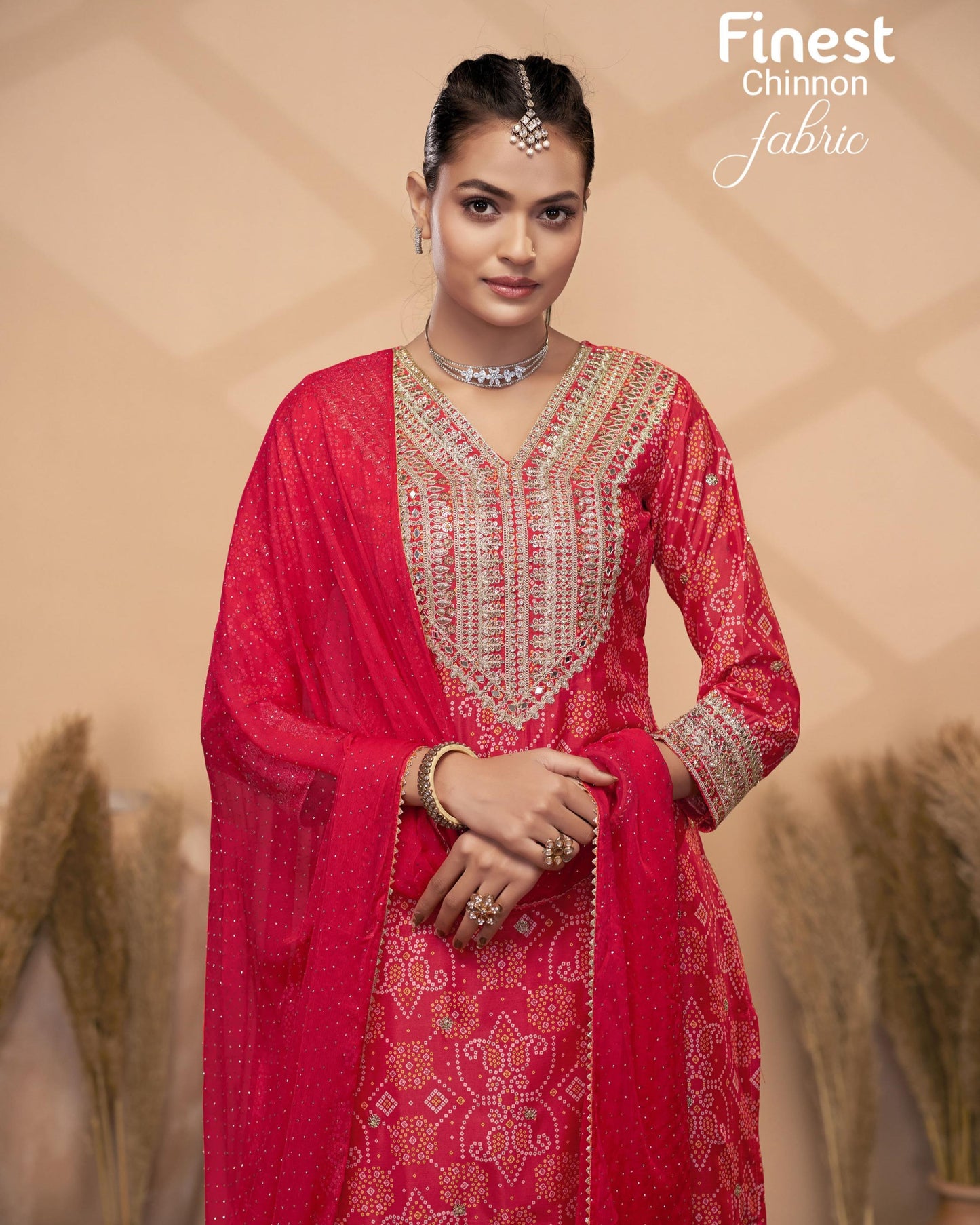 Woman wearing a red traditional outfit with intricate patterns in a decorative setting.