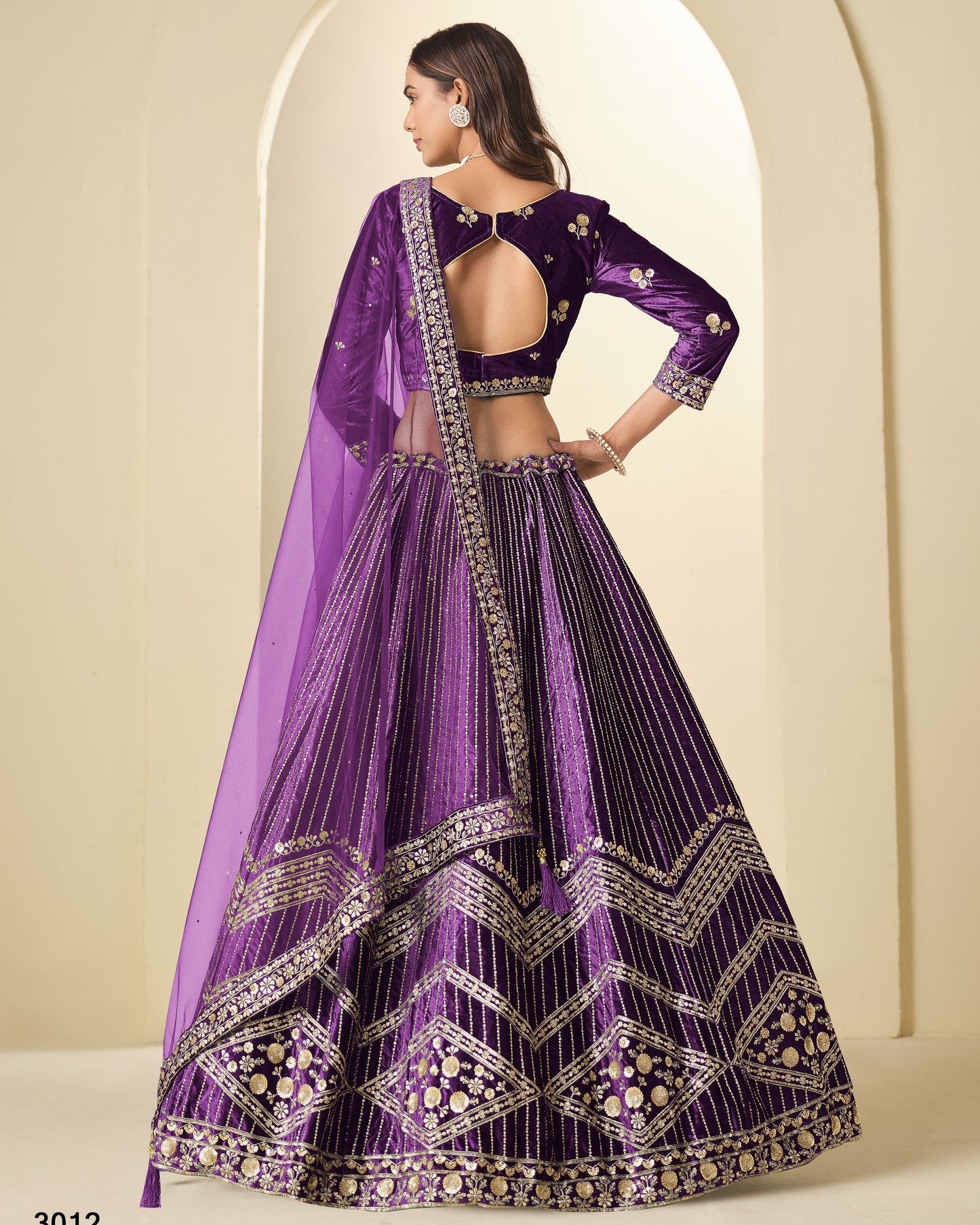 Purple embroidered traditional outfit with a sheer dupatta against a beige background
