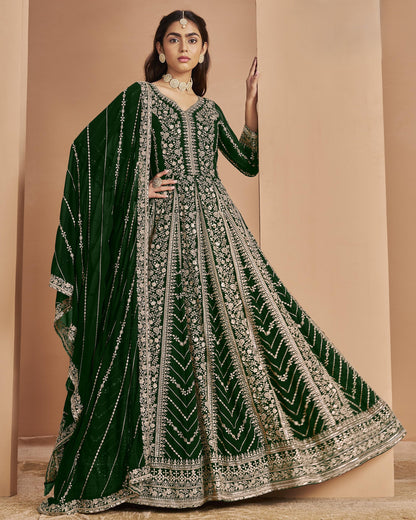 Woman wearing a green and silver embroidered traditional outfit against a beige background