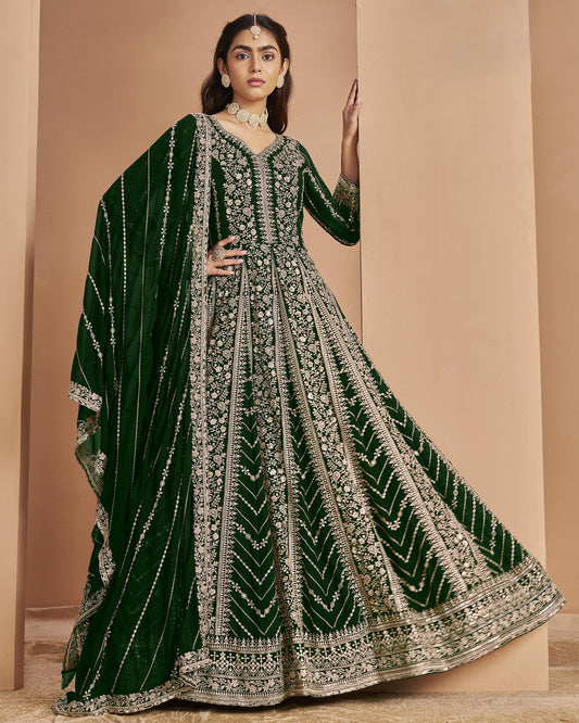 Woman wearing a green and silver embroidered traditional outfit against a beige background