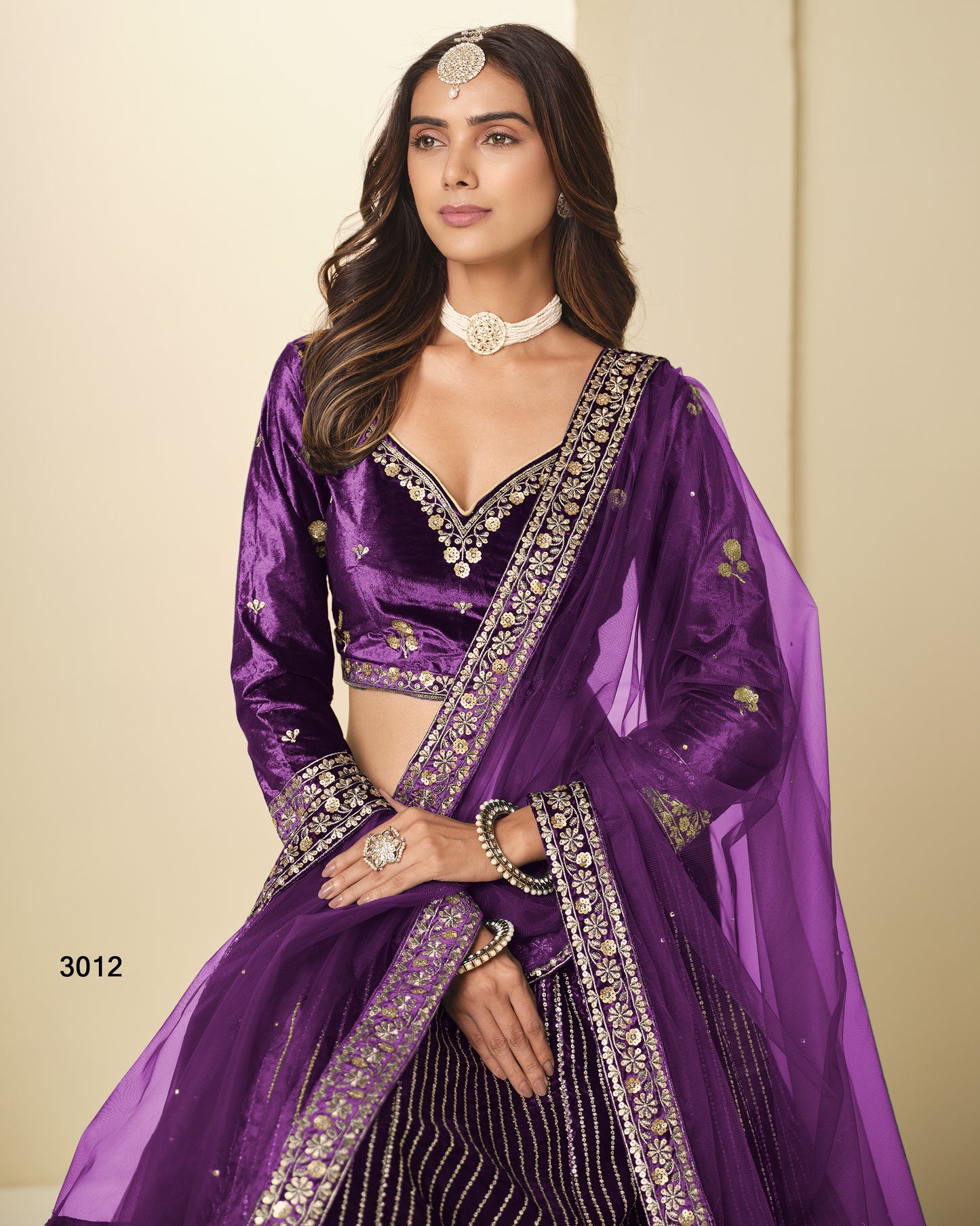 Woman wearing a purple traditional outfit with intricate designs on a beige background