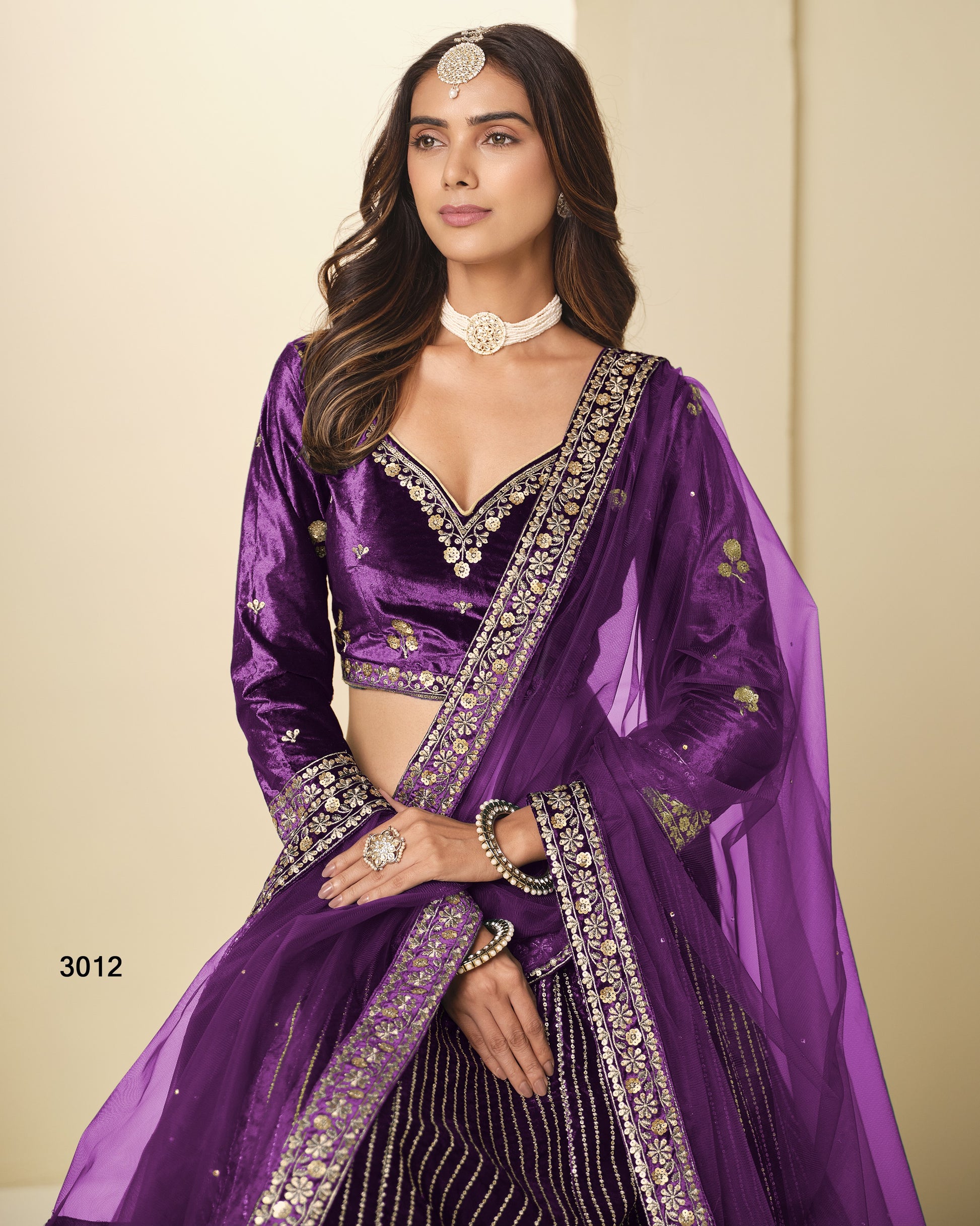Woman wearing a purple traditional outfit with intricate designs on a beige background