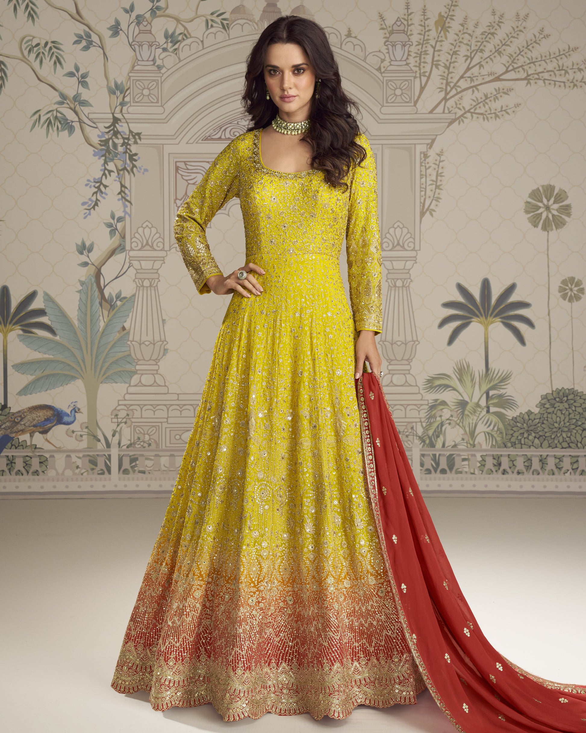 Woman wearing a yellow and red embroidered traditional outfit with a patterned wall in the background