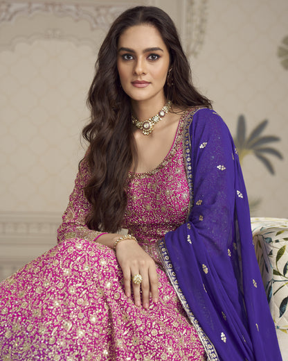 Woman in a pink and purple traditional outfit with jewelry, sitting on a decorative chair.
