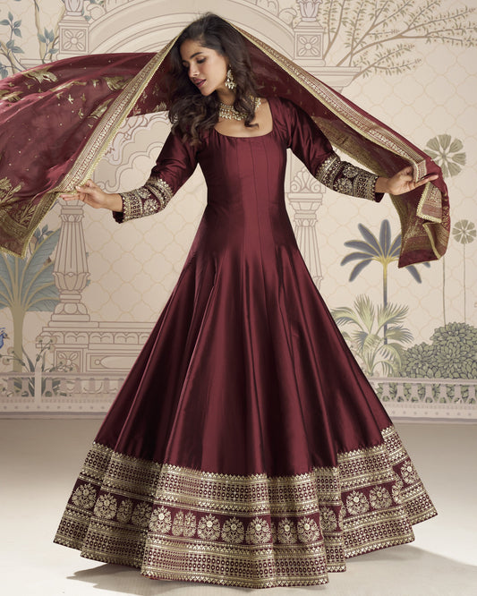 Maroon traditional outfit with gold embroidery against a decorative background