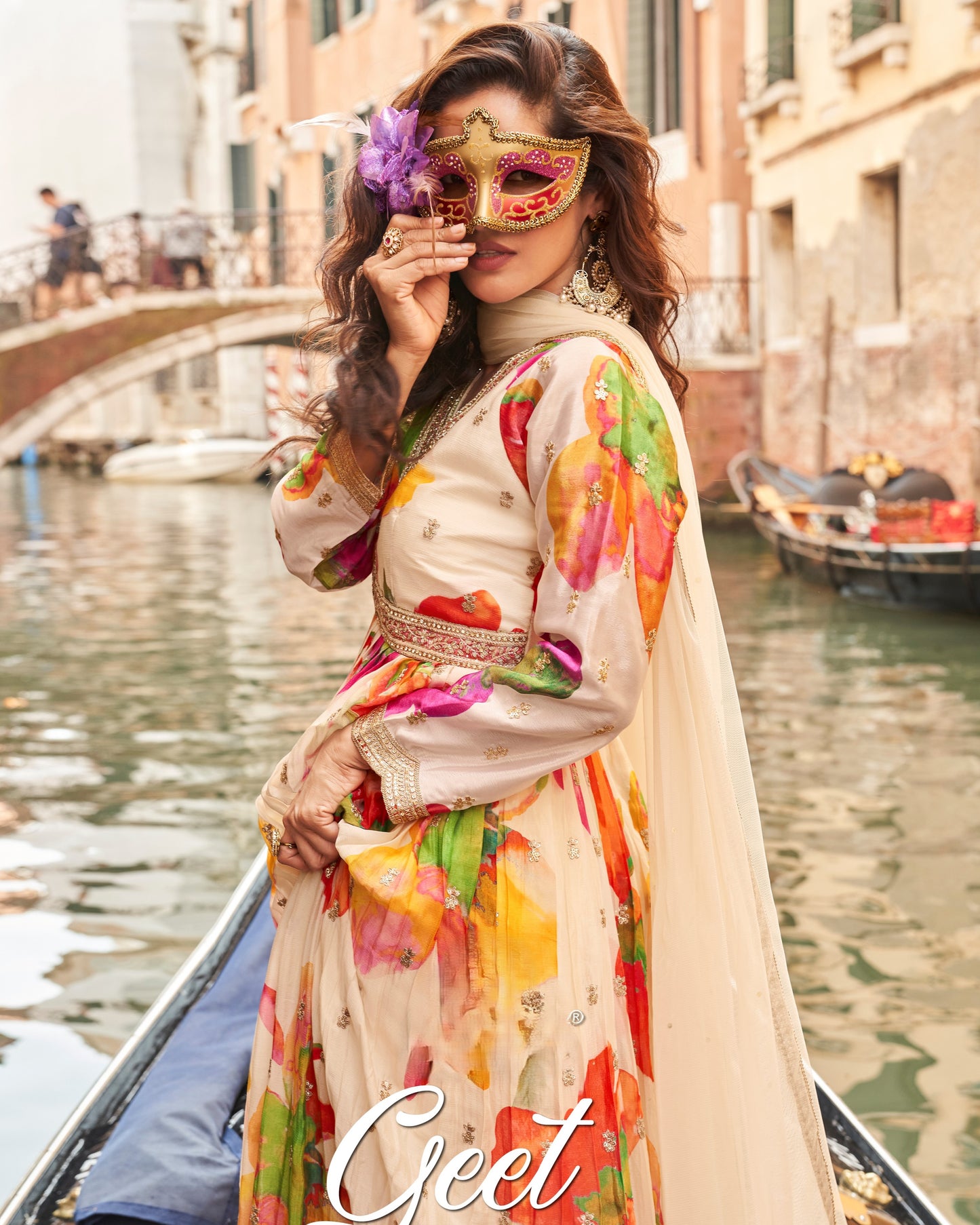 Woman in a colorful dress and mask on a gondola in Venice