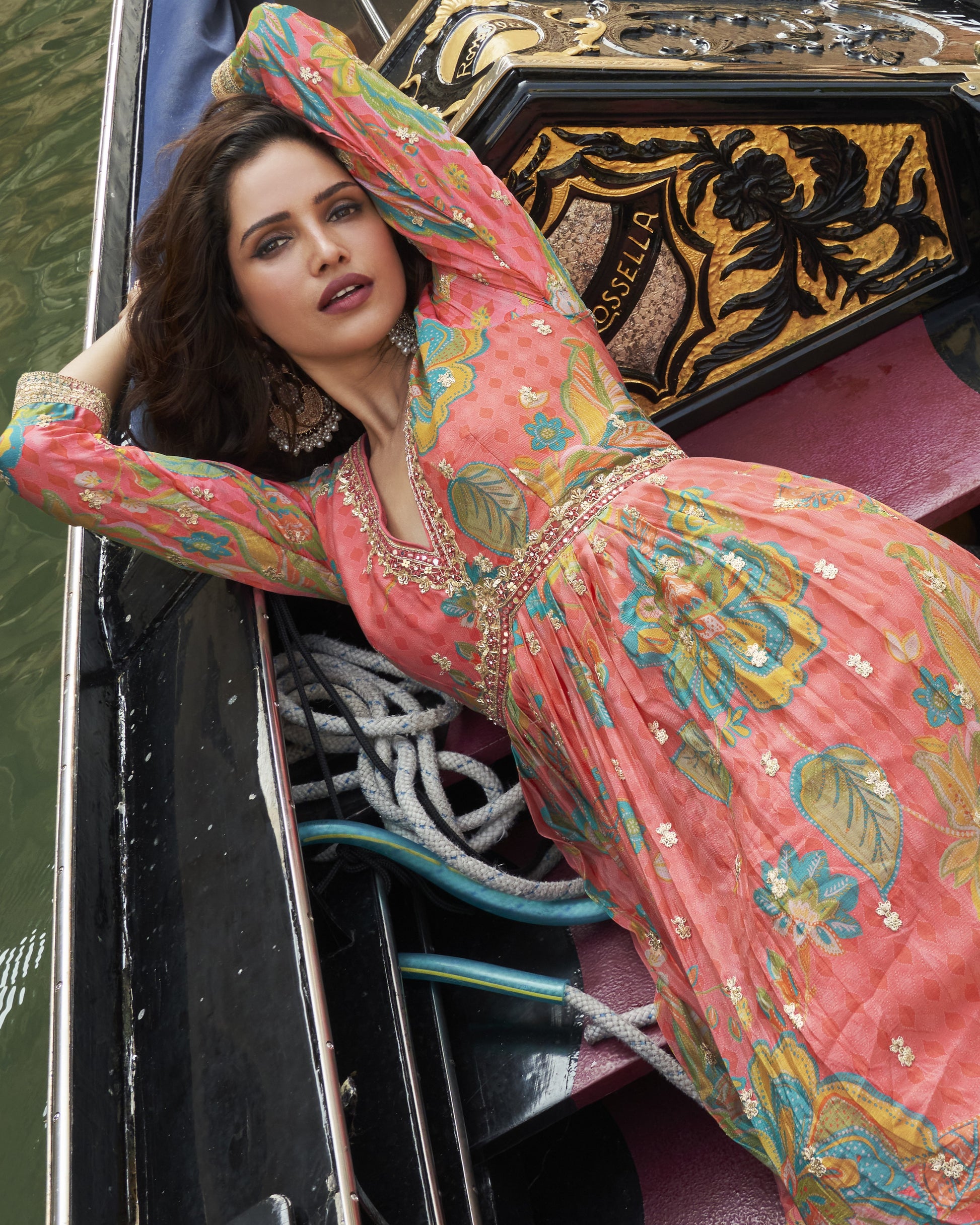 Woman in a colorful dress leaning against a gondola in Venice