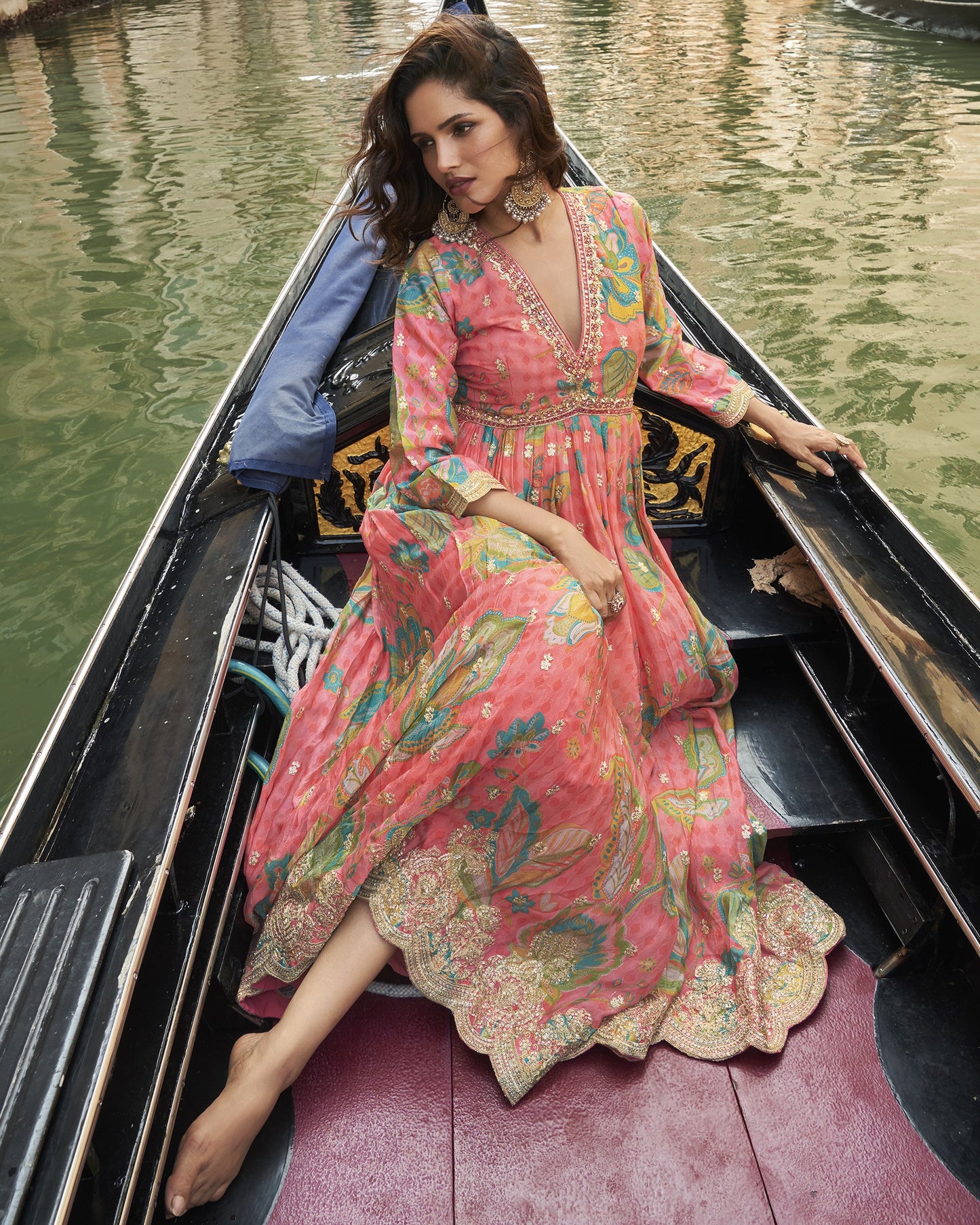 Woman in a colorful dress sitting in a gondola on a canal.