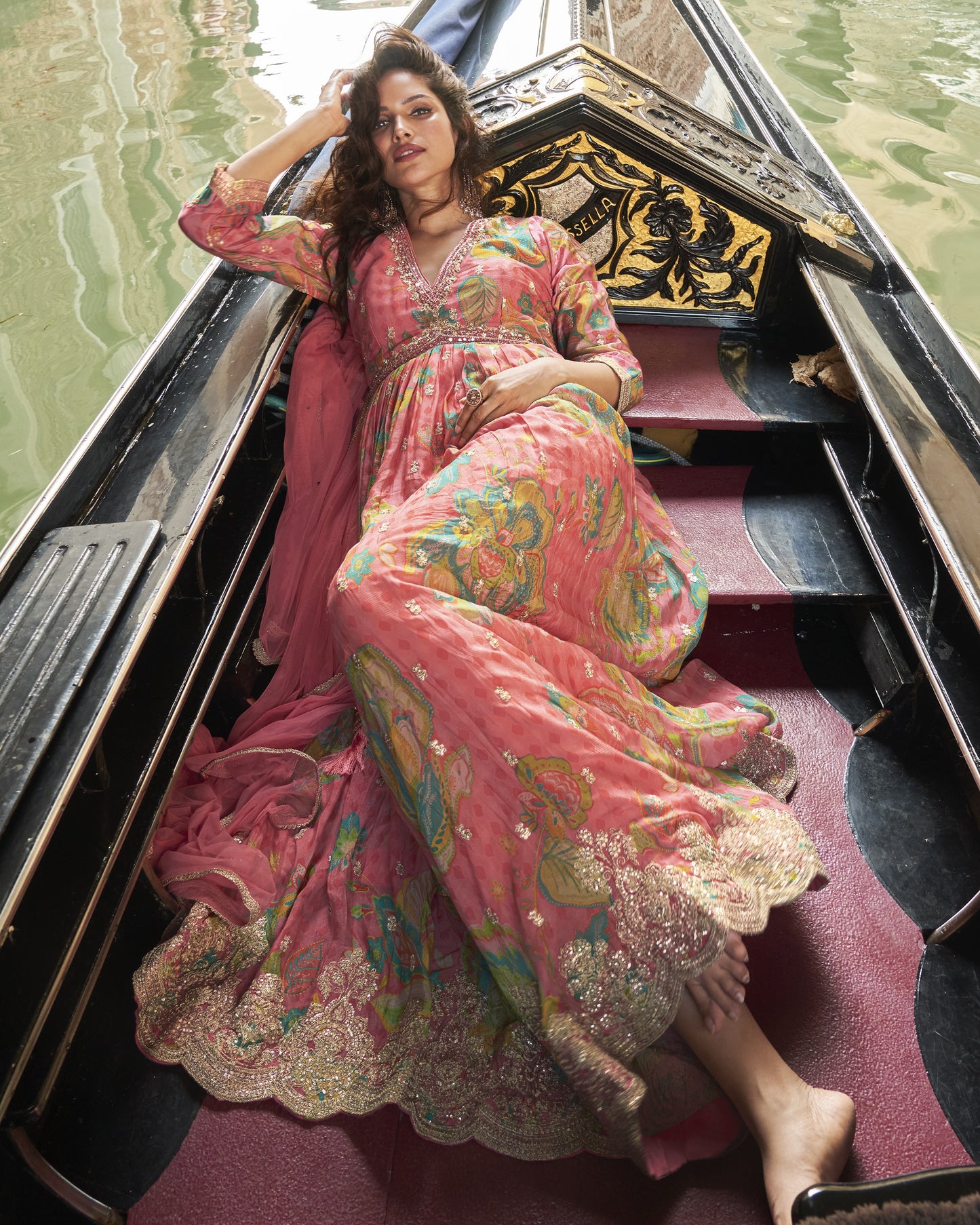 Woman in a colorful dress sitting in a gondola on water.