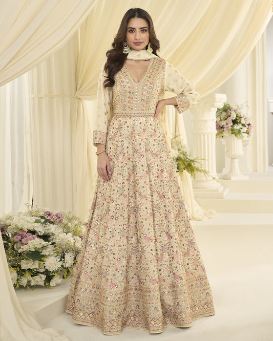 Woman in a floral dress standing in a decorated indoor setting with flowers and curtains.