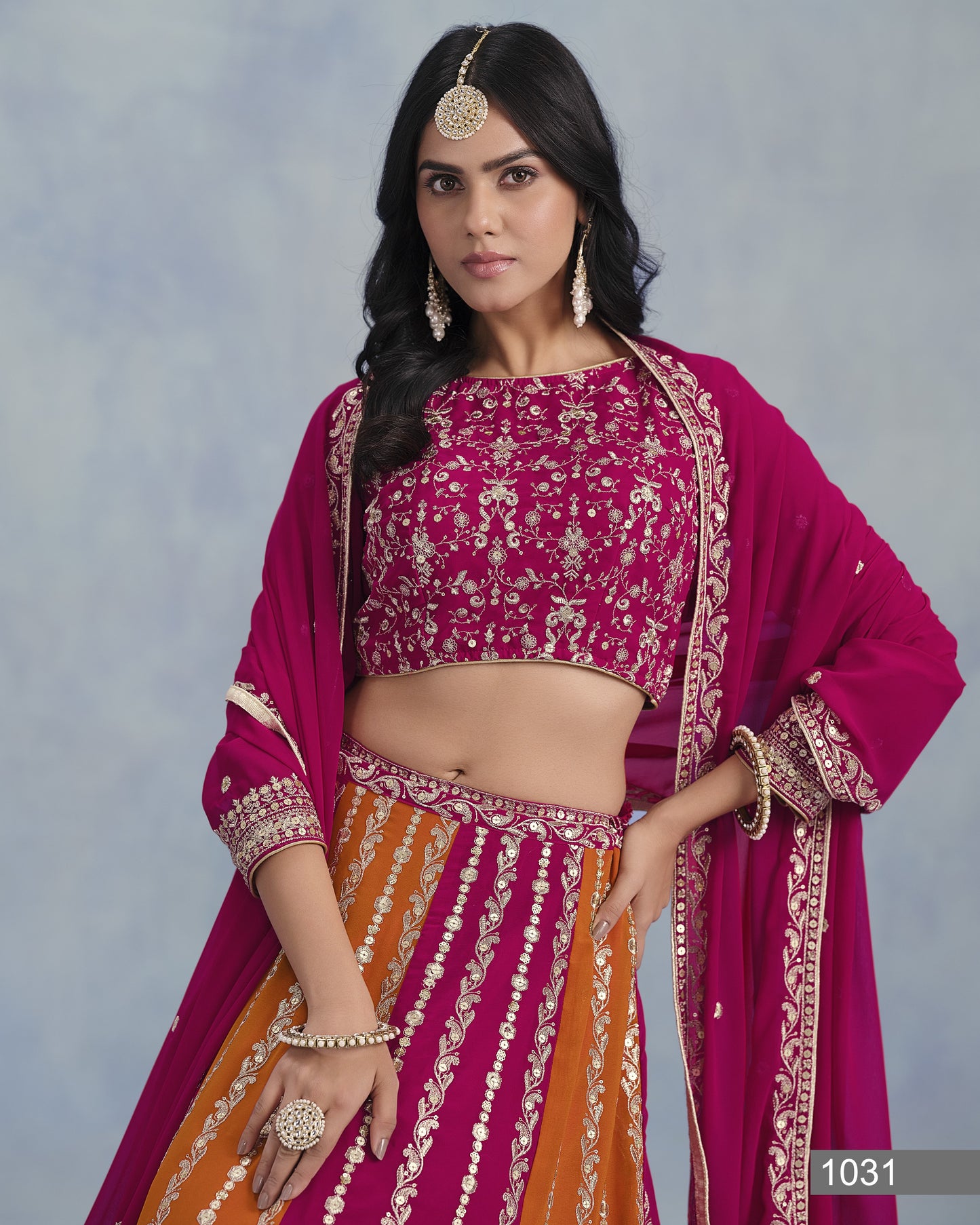 Woman wearing a traditional outfit with a pink blouse and orange skirt against a gray background