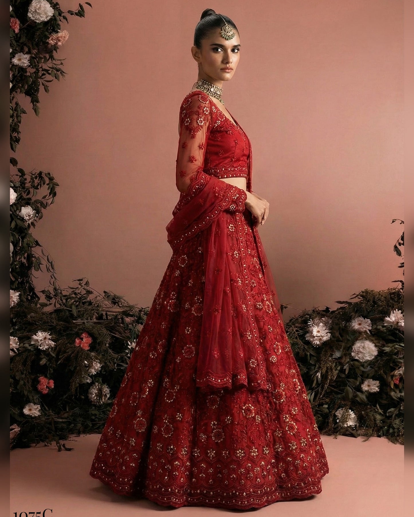 Red embroidered traditional outfit with floral decorations on a pink background