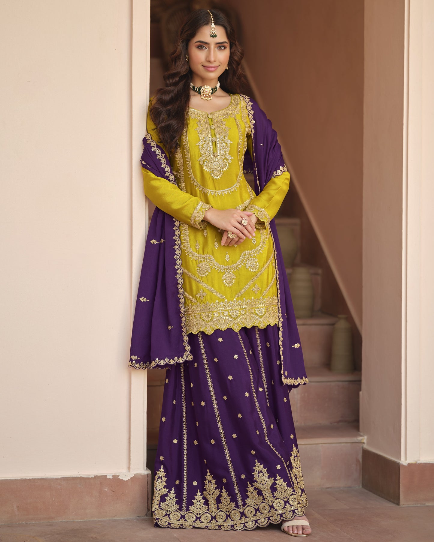 Woman wearing a yellow and purple traditional outfit with intricate designs.