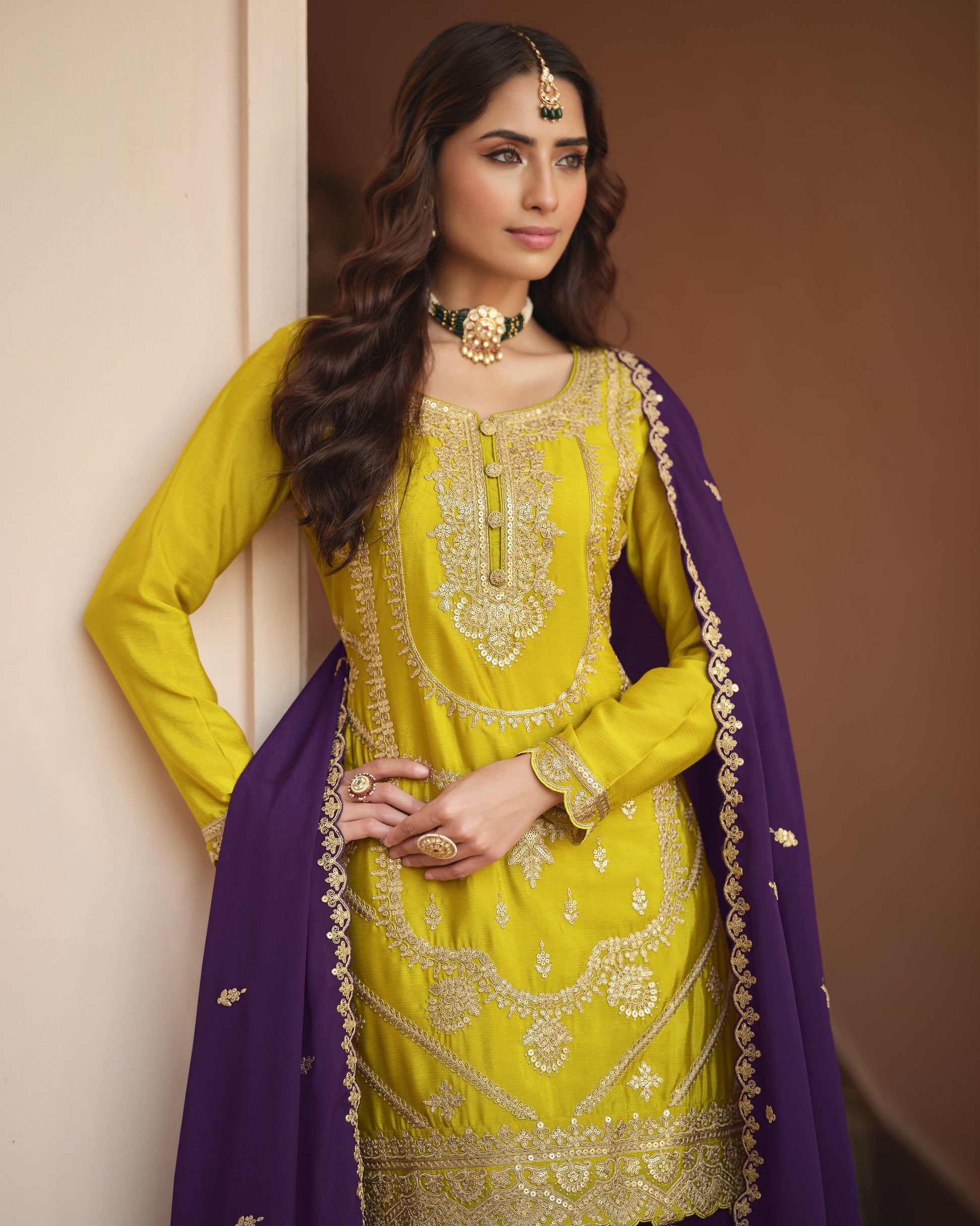 Woman wearing a yellow and purple traditional outfit with intricate designs.