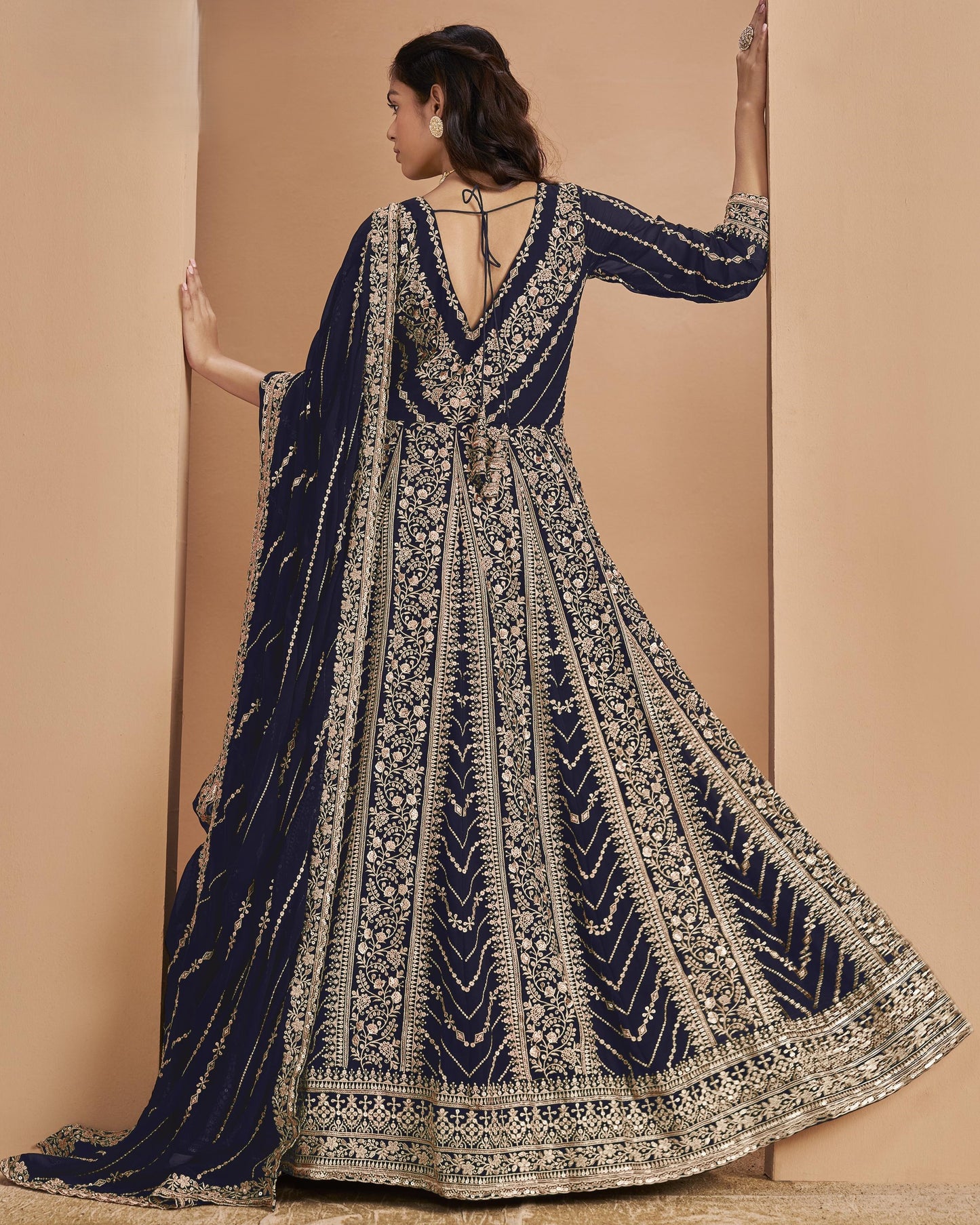 Navy blue and gold embroidered traditional outfit on a beige background