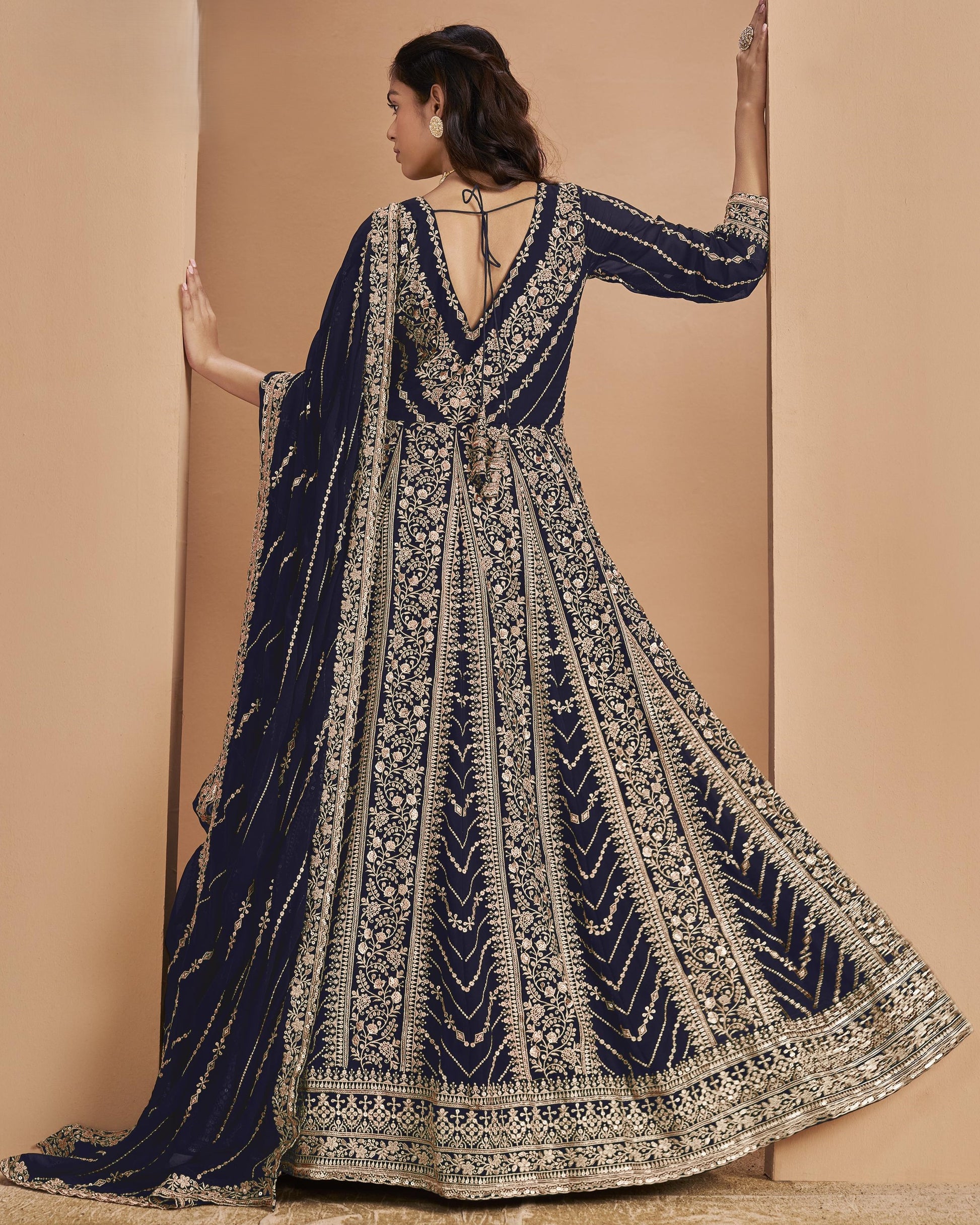 Navy blue and gold embroidered traditional outfit on a beige background