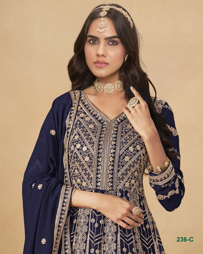 Woman wearing a navy blue and gold embroidered traditional outfit with jewelry on a beige background