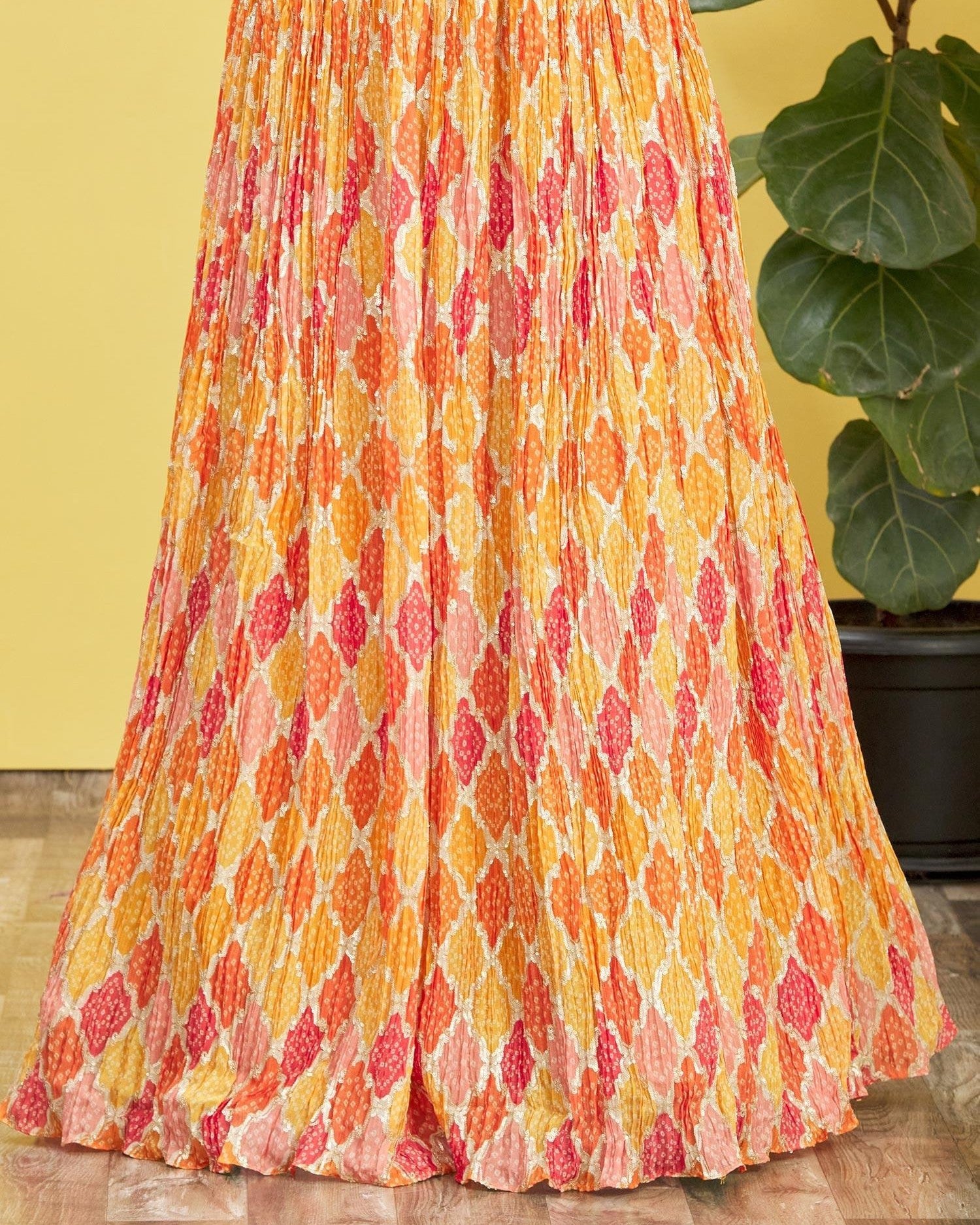 Colorful patterned skirt on a wooden floor with a yellow wall and plant in the background