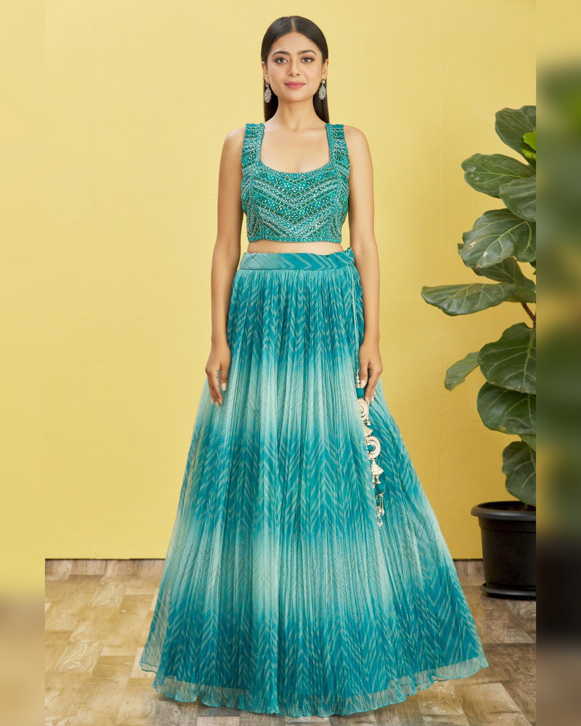 Woman wearing a green and blue gradient traditional outfit with a yellow background