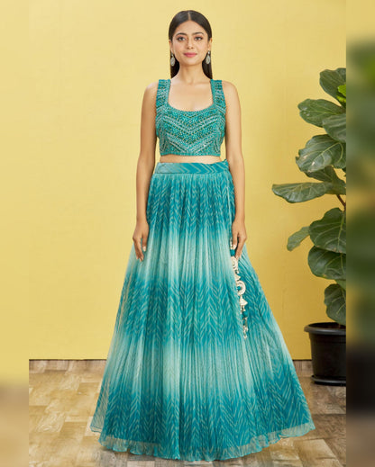 Woman wearing a green and blue gradient traditional outfit with a yellow background