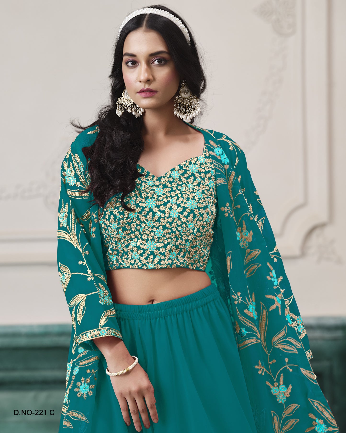 Woman wearing a green traditional outfit with floral patterns against a neutral background