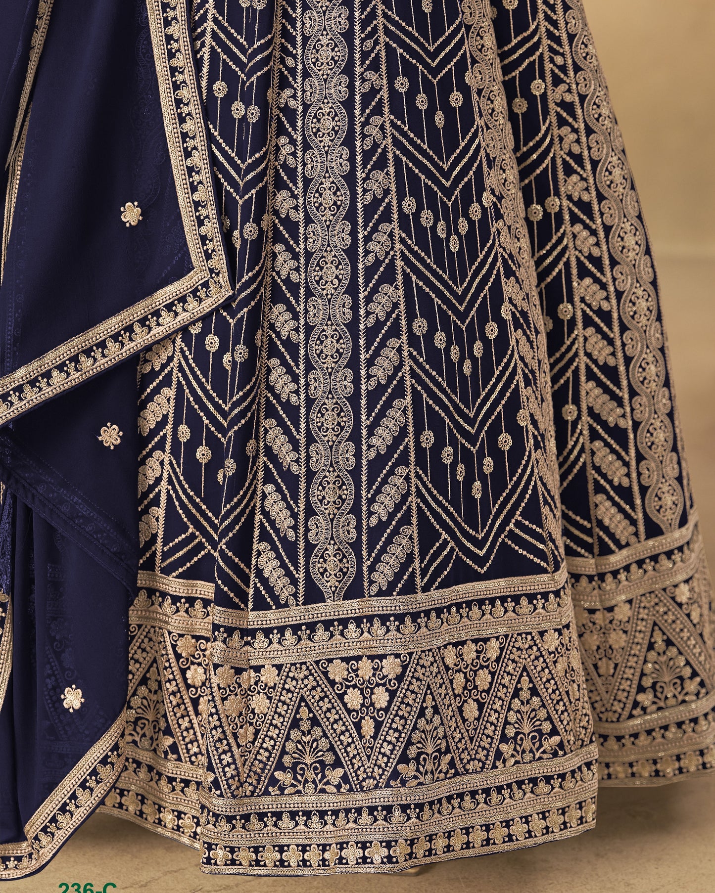 Navy blue fabric with intricate gold embroidery on a beige background