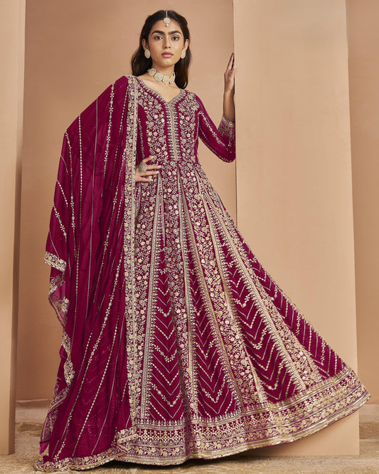 Woman wearing a maroon embroidered traditional outfit with a beige background