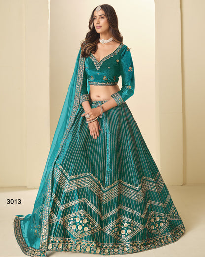 Woman wearing a teal embroidered lehenga with a matching dupatta against a beige background