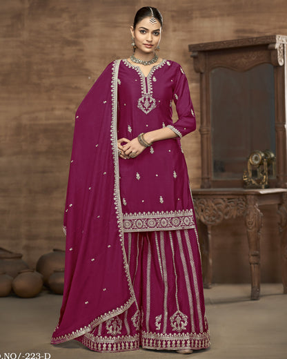 Woman wearing a traditional pink outfit with intricate white embroidery in a warm-toned room.