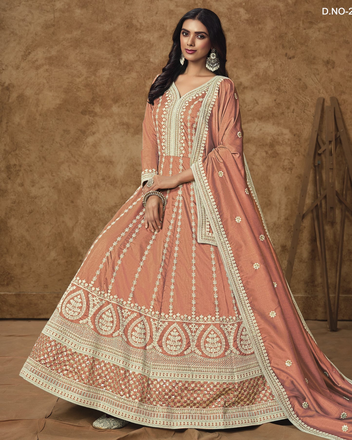 Woman wearing a traditional pink and gold embroidered outfit against a brown background