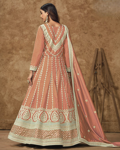 Woman wearing a traditional pink and white embroidered outfit against a brown background