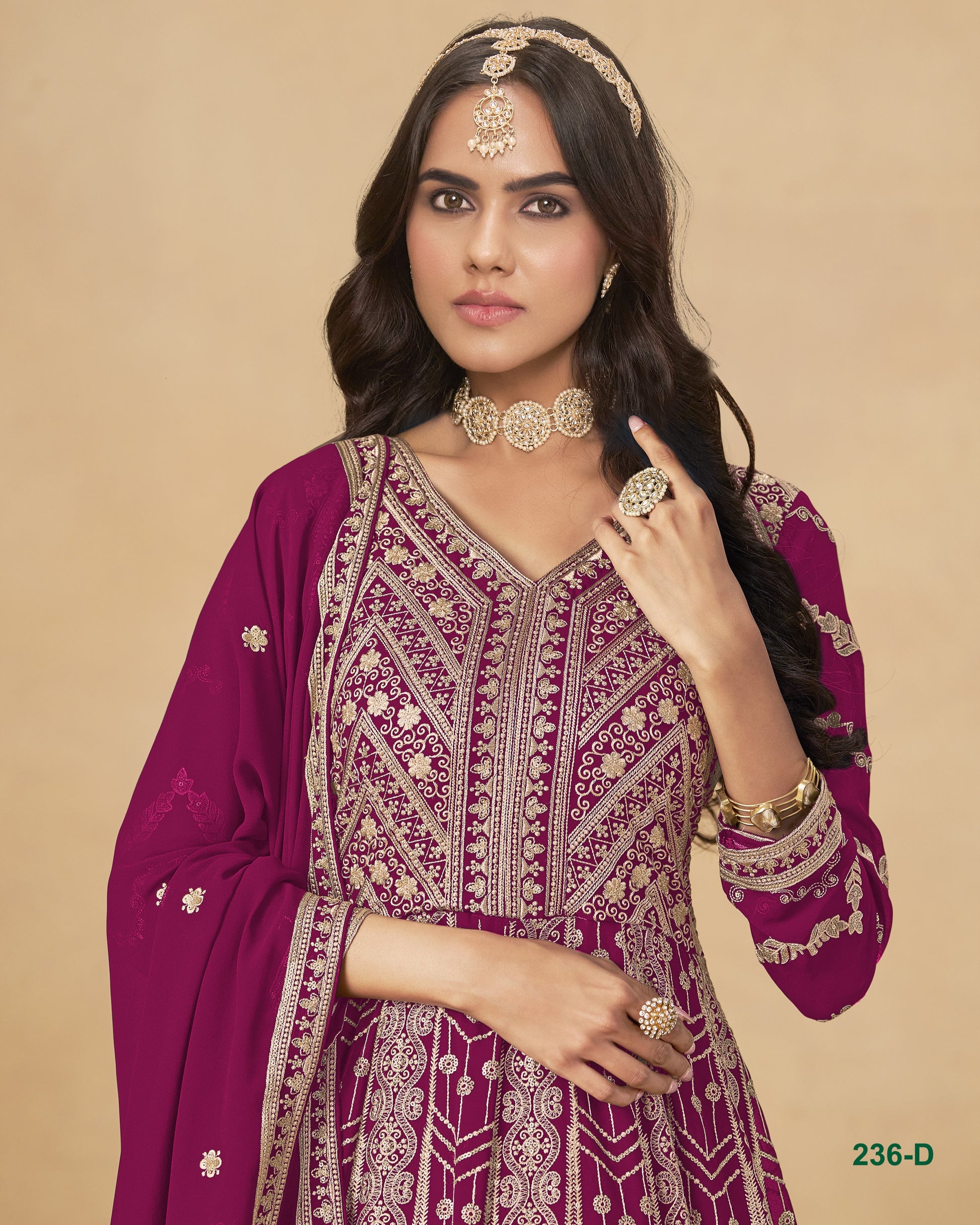 Woman wearing a purple embroidered traditional outfit with jewelry on a beige background